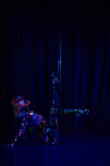 Female pole dancer in bright neon colours under ultraviolet (UV) light on background