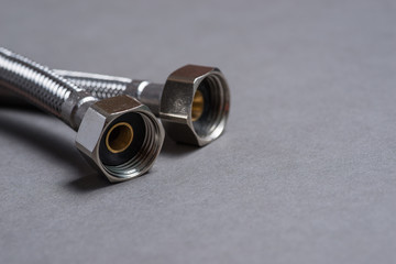 Braided stainless steel water hose over grey background