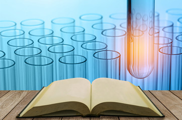 open book on wooden table with science laboratory test tubes bac