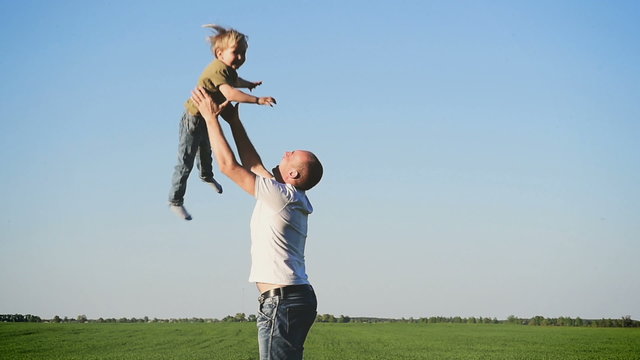 dad throws baby son into the sky. In nature. Slow motion.