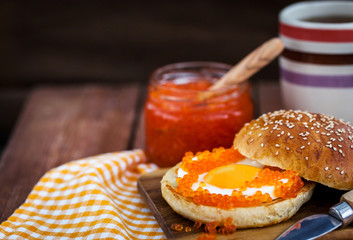 Fried egg with red caviar on a bun