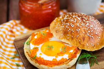 Fried egg with red caviar on a bun