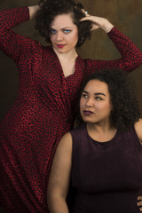 Pair of attractive young women, one Latina, the other Caucasian, having fun together against portrait background