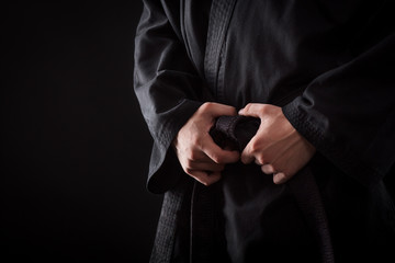Closeup of male karate fighter hands on the knot of black belt