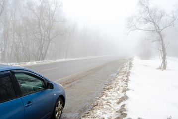 Blue car on a foggy road