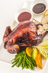 Roasted whole chicken with sauces, fruits and herbs on a plate

