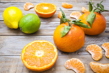 several mature citrus on a wooden table - lemon, lime and tangerine
