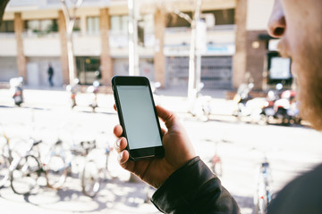Closeup image of a man holding smartphone and looking at blank white screen