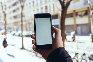 Close up of man's hands holding and using mobile smartphone with blank white screen