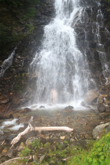 Fototapeta na wymiar Man bathing in alpine mountain waterfall in Hohe Tauern Alps, Austria