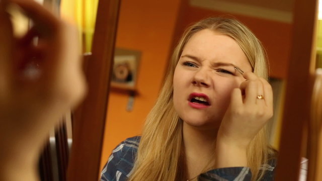Pertty girl plucking her eyebrows 
