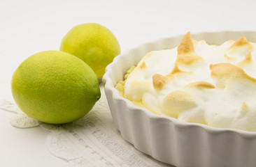 Lemon meringue pie and whole lemons on white
