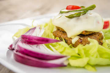 Double beef burger with melted cheese, asparagus and fresh vegetables