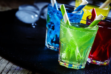 Colorful cocktails with straws on a dark background, selective f