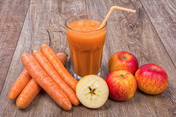 Blended orange smoothie with ingredients on wooden table
