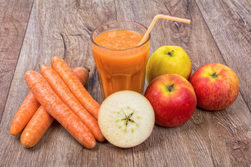 Blended orange smoothie with ingredients on wooden table