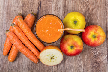Blended orange smoothie with ingredients on wooden table