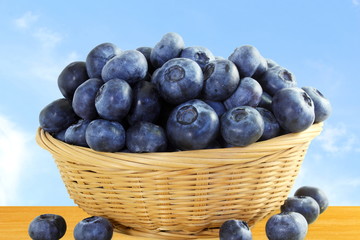 blueberries in bamboo basket closeup on sky background