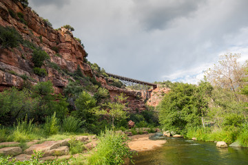 Fototapeta na wymiar Cliffs of red rock and bridge at a crossing of Oak Creek Canyon,Arizona