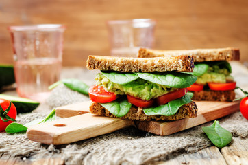 Smashed avocado spinach tomato grilled rye sandwich