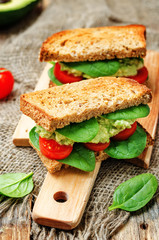 Smashed avocado spinach tomato grilled rye sandwich