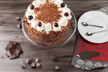 Black forest cake decorated with whipped cream and cherries. 