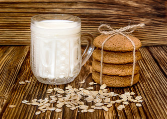 Oatmeal cookies with glass of milk on wood background