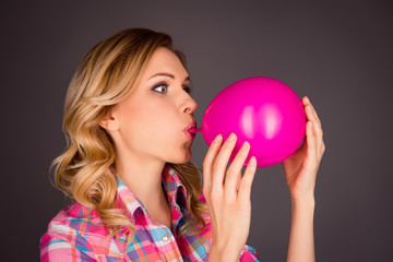 Naklejka premium Side view portrait of pretty woman blowing balloon