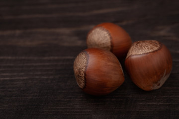 Three  hazelnuts on dark wood background