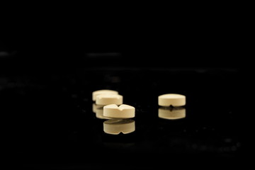 vier gelbe tabletten auf schwarzen hintergrund