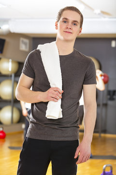 Confident and smiling young man exercising at fitness gym 