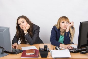 Two young employee of the office behind a desk looking sadly into the frame