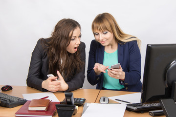 Office workers animatedly discussing personal issues and looking at mobile phone