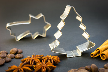 Christmas star and Christmas tree cookie cutters, anise stars, cinnamon sticks and chocolate on the...
