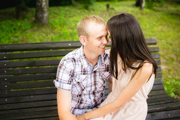 Fototapeta na wymiar Young couple sitting together on bench in the park