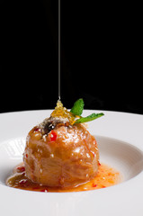 Baked apple with  honey caramel  on white ceramic plate on black background