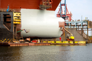 Painting the hull of the ship at the dock during the renovation in Gdansk Repair Shipyard