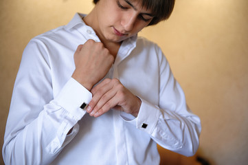 groom wears cuff links on white shirt