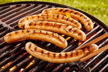 Pork sausages grilling on a portable BBQ