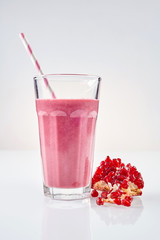 Pomegranate smoothie in tall glass next to fruit