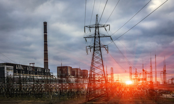 thermal power plant with pipes and power lines at sunset