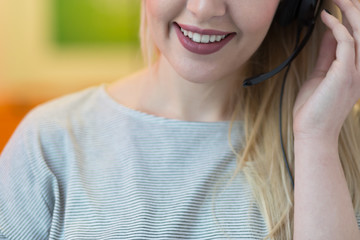 Smiling young business woman wearing a headset answering calls a