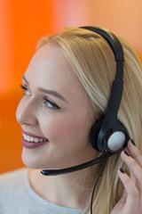 Smiling young business woman wearing a headset answering calls a