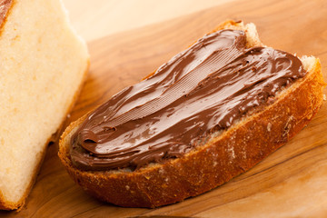 Slice of bread with sweet chocolate nougat spread on wooden back