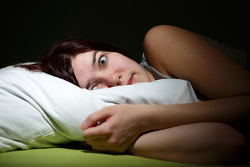 Young woman in bed  eyes opened suffering insomnia. Nightmare issues