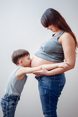 Little boy kissing belly of pregnant mom