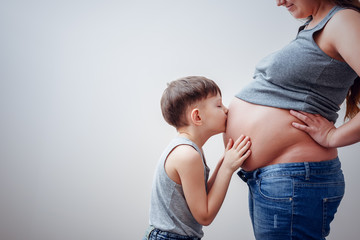 Little boy kissing belly of pregnant mom