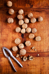 Fototapeta na wymiar Walnuts with nutcracker on rustic wooden background