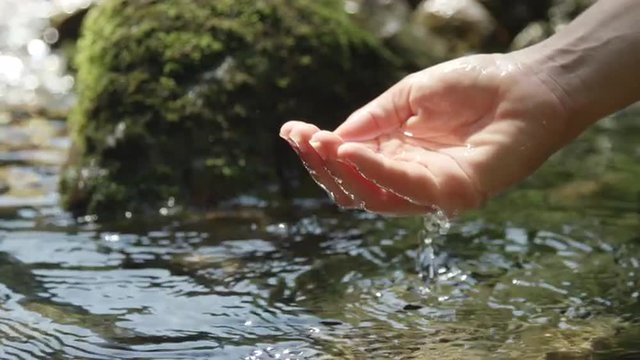 SLOW MOTION: Hand scooping fresh water in pure mountain spring