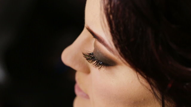 Proffessional make up artist glues false eyelashes to a bride for her wedding celebration.